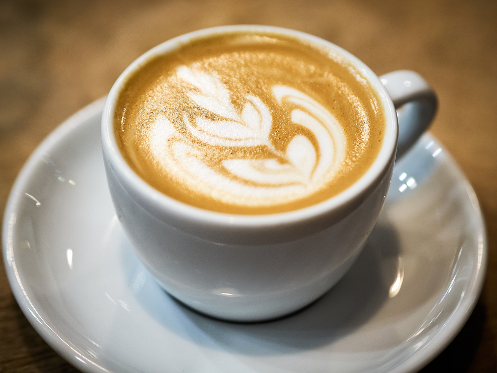 Cappuccino with delicate latte art on a white saucer