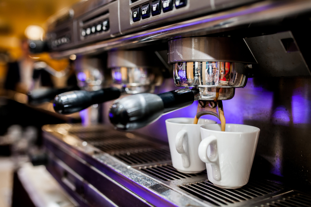 Two white cups filling under the espresso machine