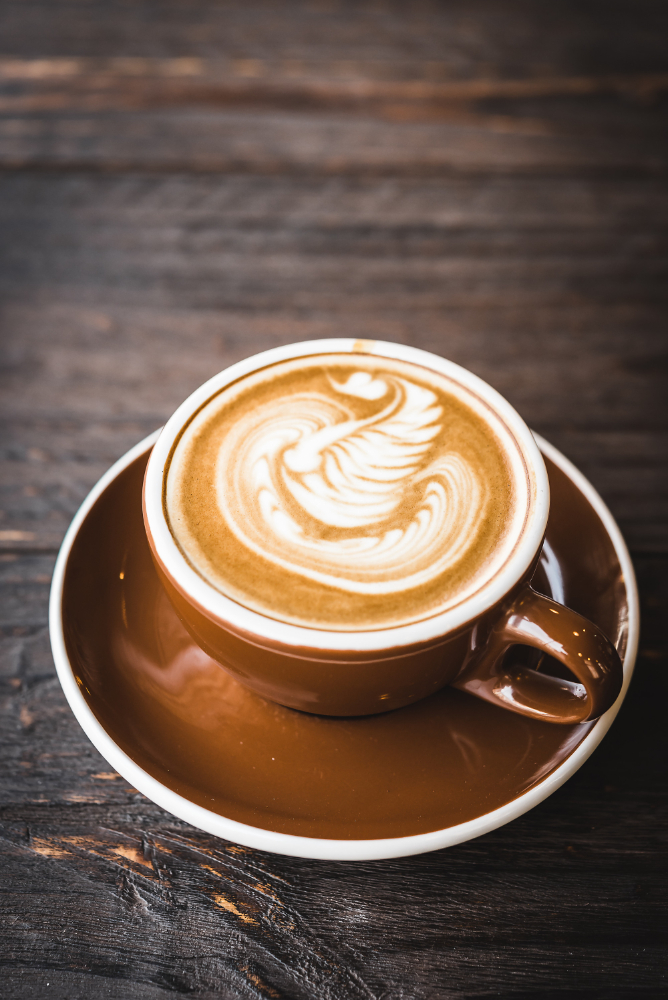 Flat white in a brown cup on a rustic wood table