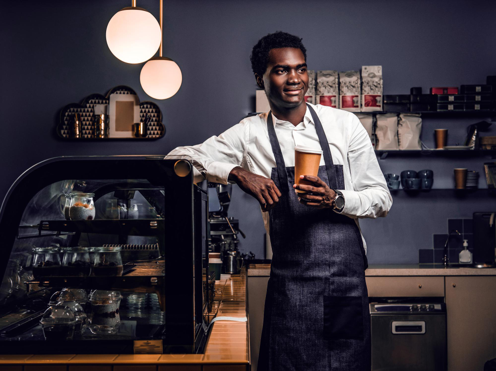 Barista holding a takeaway coffee at the counter