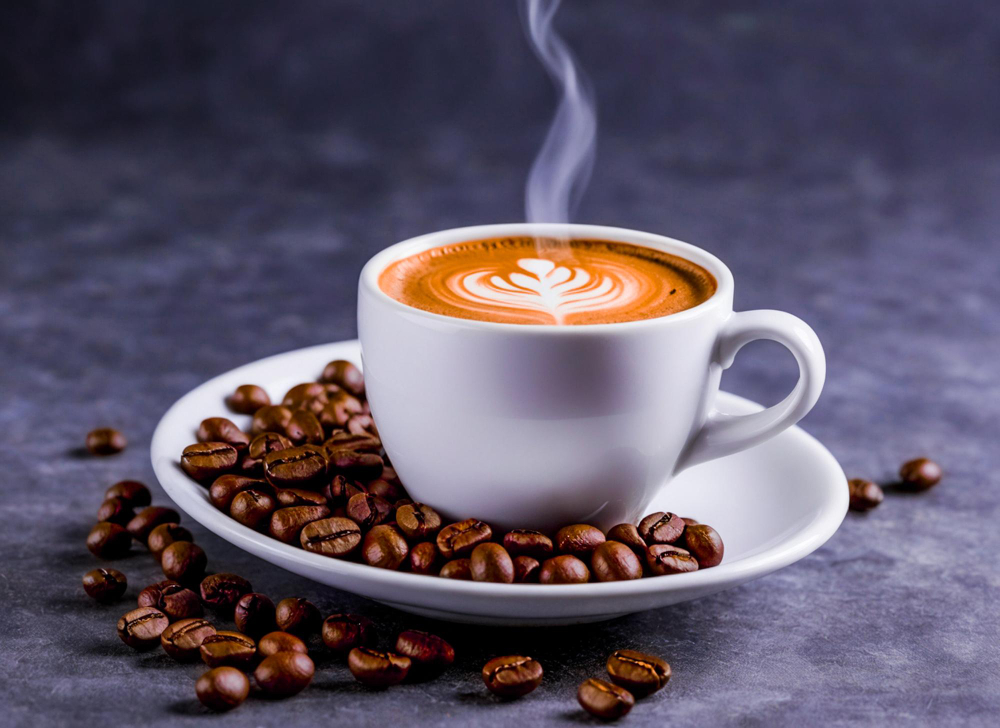 Espresso with latte art beside roasted coffee beans